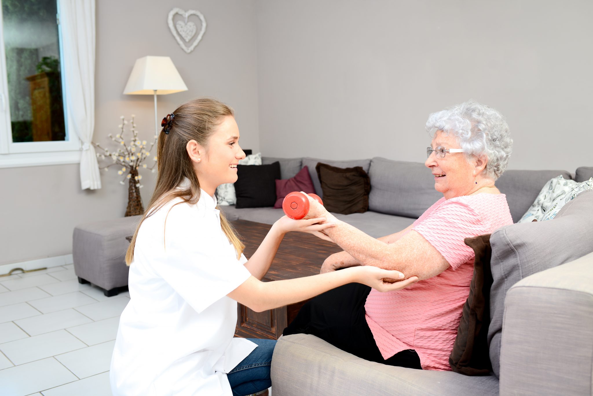young physiotherapist nurse helping elderly women physical rehabilitation at home